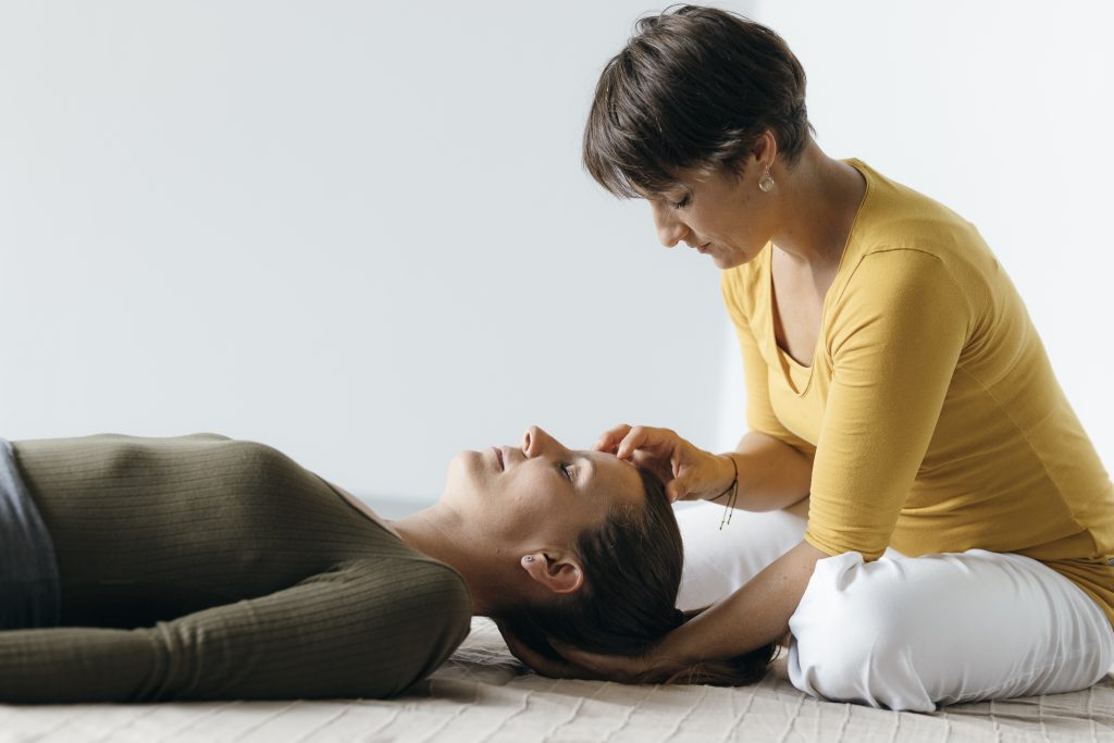 Shiatsu-Behandlung: Praktikerin hält achtsam den Kopf einer liegenden Frau